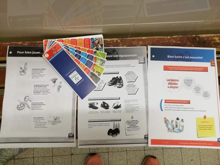 Trois affiches d'information sur le bien-être et l'équipement sportif, avec des cartes colorées posées dessus.
