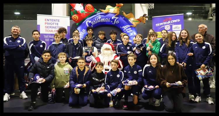 Un groupe de jeunes footballeurs et d'adultes posent avec le Père Noël devant une arche gonflable de Noël.