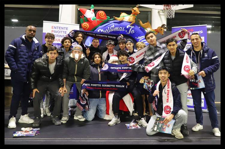 Un groupe de jeunes joueurs et d'adultes posent ensemble, tenant des écharpes de club, devant une décoration de Noël.