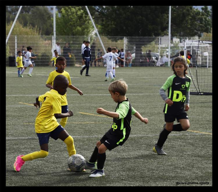 Des jeunes joueurs de football s'affrontent sur le terrain lors d'un match ou d'un entraînement.