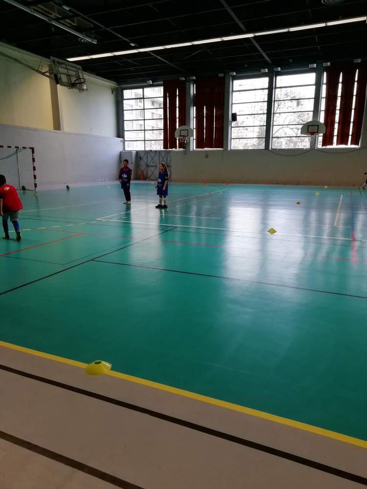 Des jeunes joueurs de football en salle s'entraînent sur un terrain vert avec des cônes.