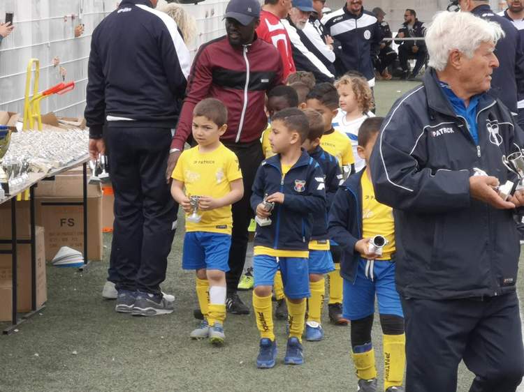 Des jeunes joueurs de football en tenue de sport, tenant des trophées, lors d'une cérémonie de remise de prix.