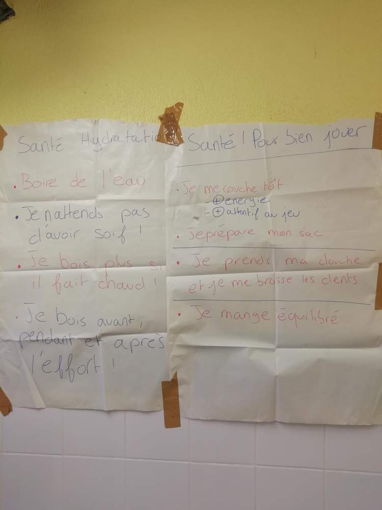Deux feuilles de papier affichant des conseils de santé et d'hydratation pour les joueurs, scotchées sur un mur.