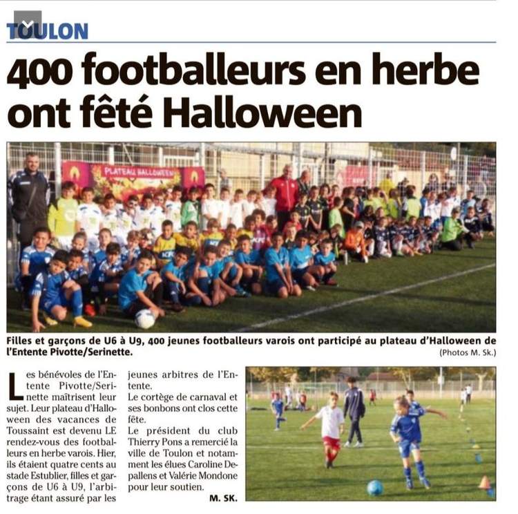 Un grand groupe d'enfants et quelques adultes posent pour une photo de groupe sur un terrain de football.