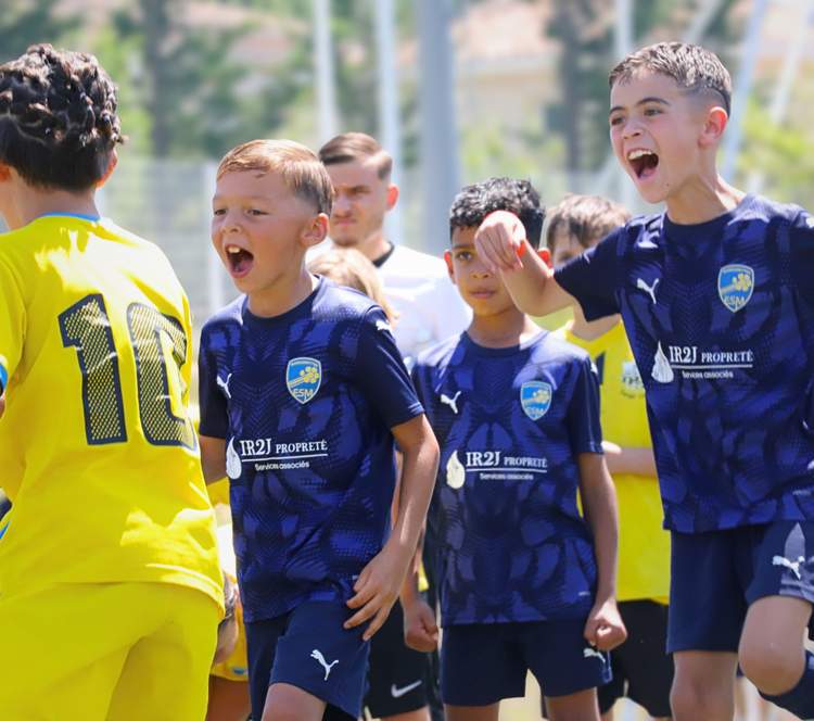 Des jeunes joueurs de football en maillots bleus et jaunes crient de joie ou d'effort sur le terrain.