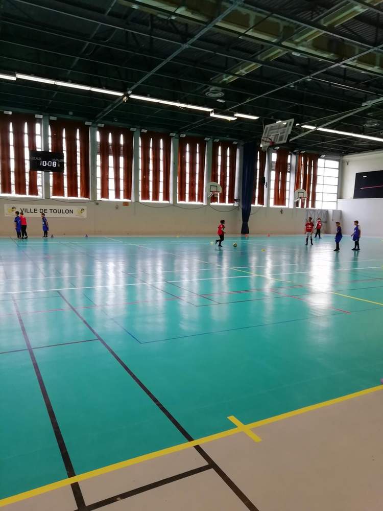 Des jeunes joueurs de football s'entraînent sur un terrain de sport en salle.