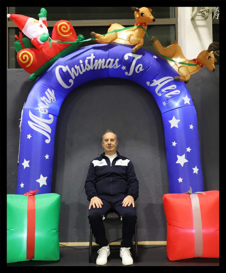 Un homme est assis devant une arche gonflable de Noël avec des cadeaux.
