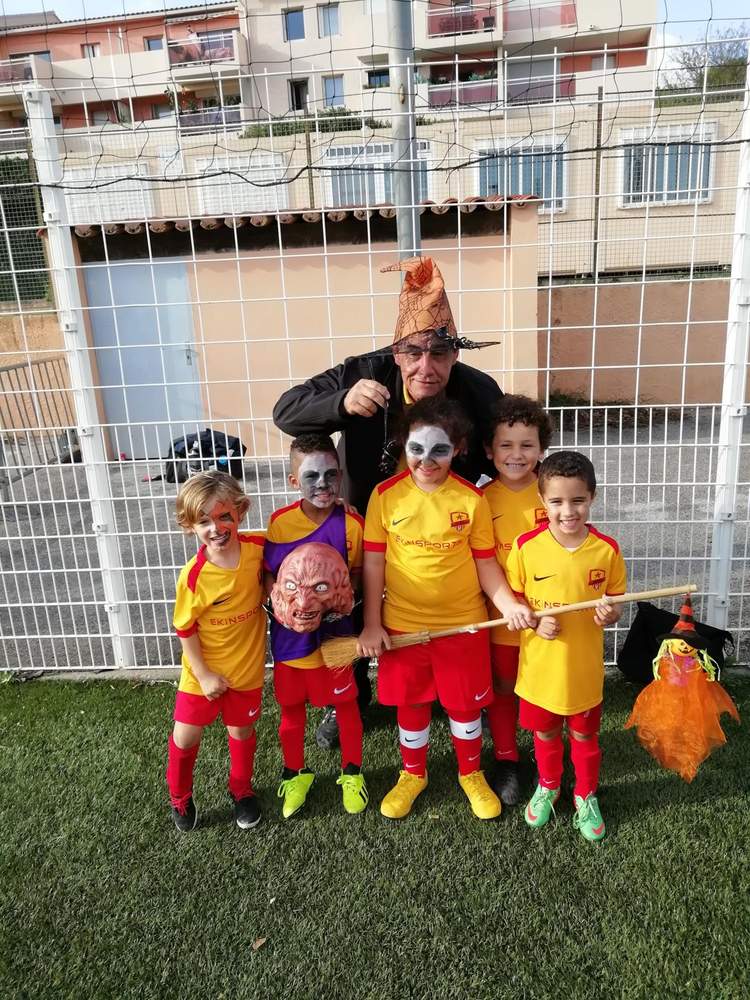 Un groupe d'enfants déguisés pour Halloween avec un adulte sur un terrain de football.