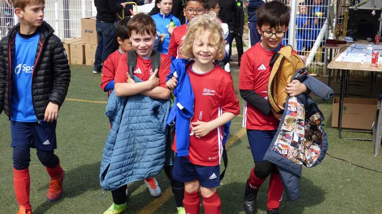 Des jeunes joueurs de football en tenue de sport se tiennent sur un terrain, certains souriant à l'appareil.