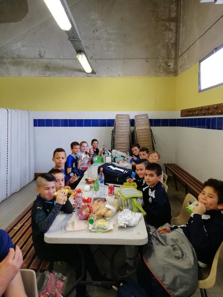 Des jeunes footballeurs partagent un repas convivial autour d'une table après un match ou un entraînement.