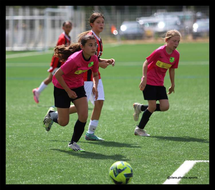 Des jeunes joueuses de football courent sur le terrain pendant un match ou un entraînement.
