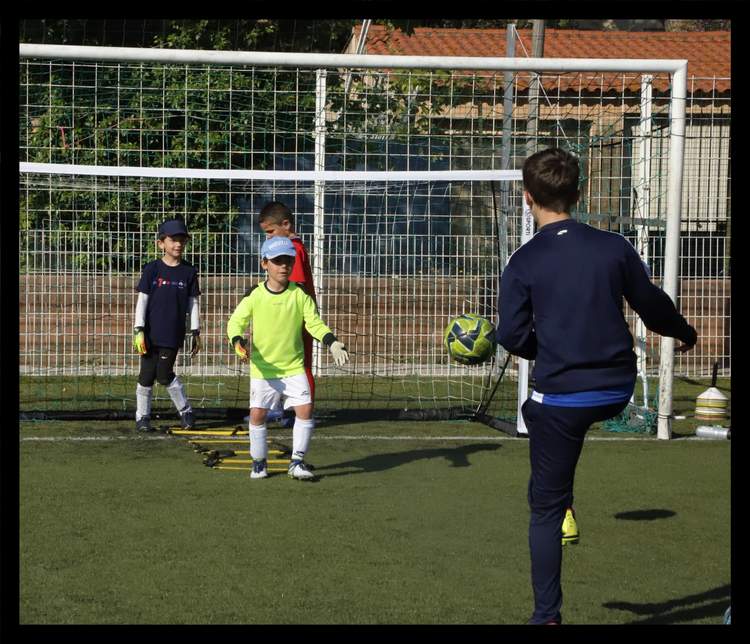 Des jeunes joueurs de football s'entraînent au tir au but sur un terrain synthétique.