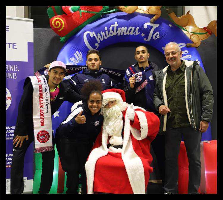 Des membres du club posent avec le Père Noël devant une arche gonflable de Noël.