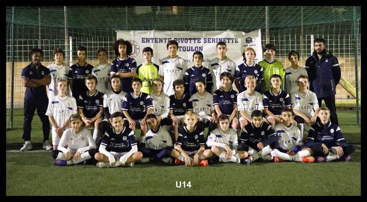 Une équipe de jeunes footballeurs pose avec leurs entraîneurs devant une banderole sur un terrain de nuit.