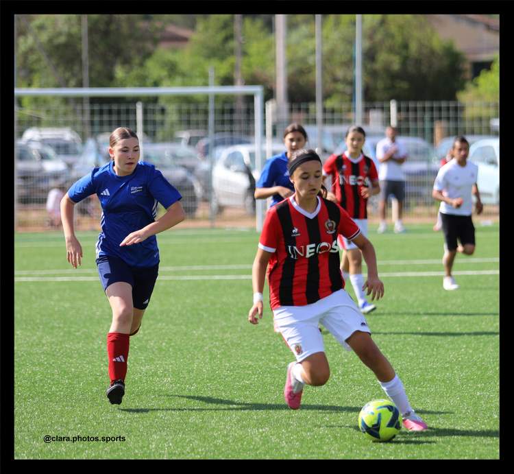 Des joueuses de football féminin en pleine action sur un terrain en herbe synthétique.