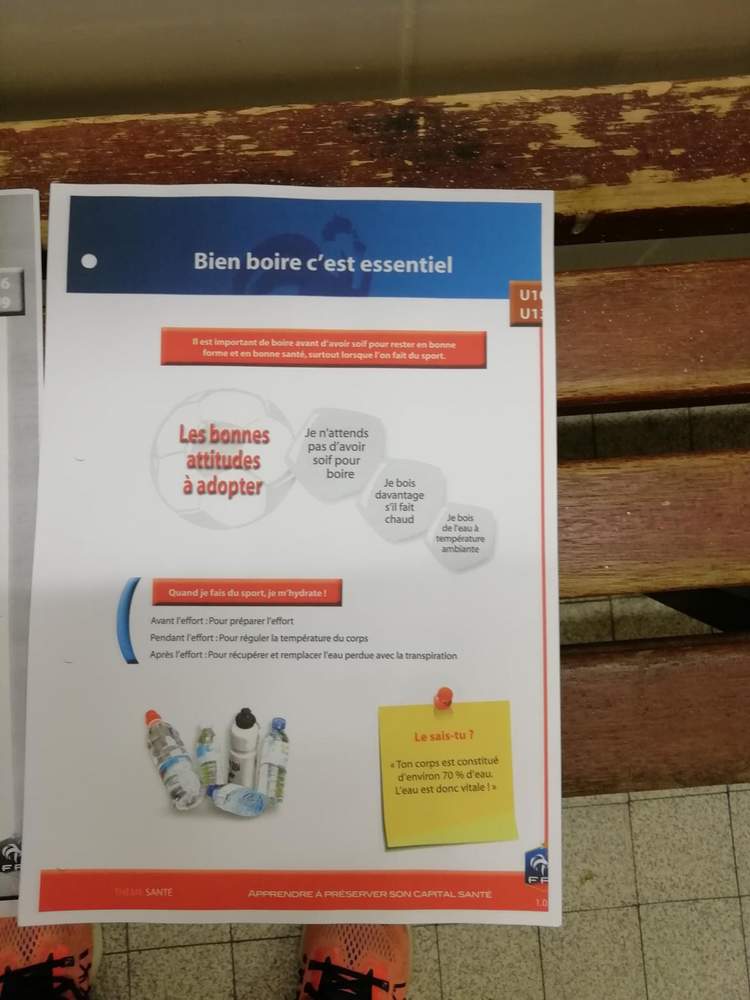 Un document imprimé sur l'importance de bien s'hydrater pour le sport, posé sur un banc en bois.