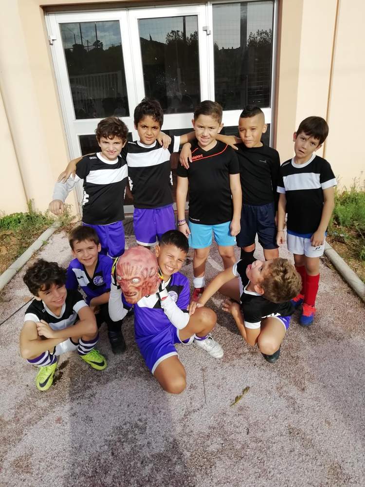 Un groupe de jeunes footballeurs pose avec des sourires, certains tenant un masque effrayant.