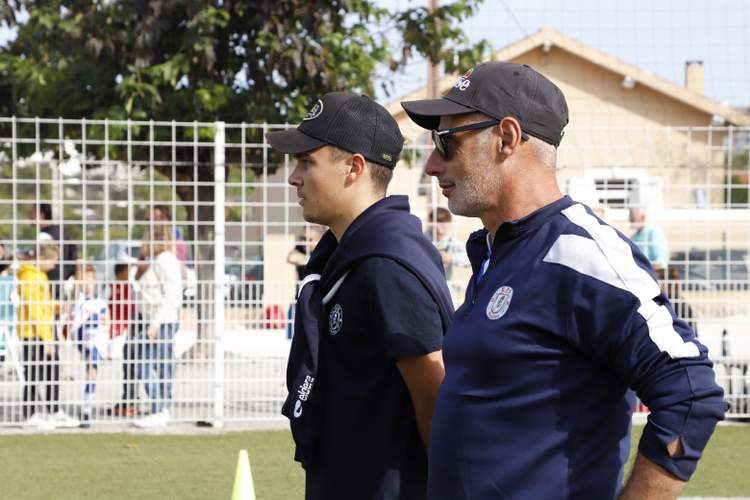 Deux hommes en tenue de sport regardent un événement sportif sur un terrain de football.
