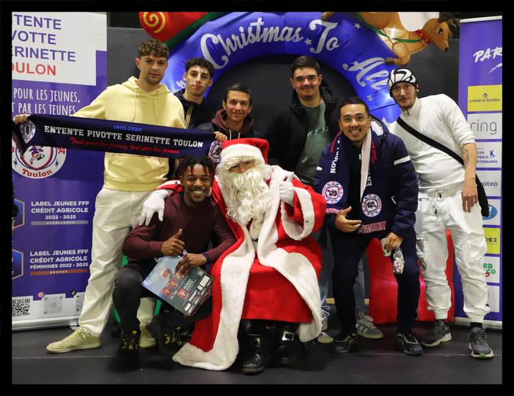 Un groupe de jeunes hommes pose avec le Père Noël devant une arche gonflable de Noël et des bannières de club.