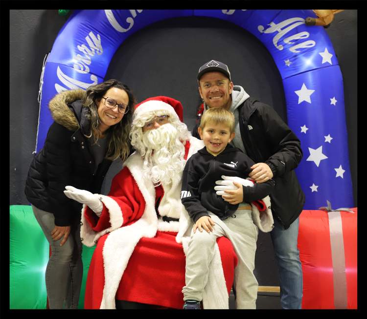 Une famille pose avec le Père Noël devant une arche gonflable décorée d'étoiles.