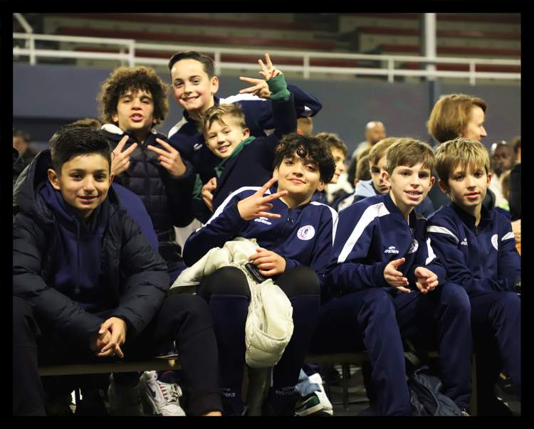 Un groupe de jeunes joueurs de football souriants et posant pour la photo, vêtus de leurs survêtements de club.