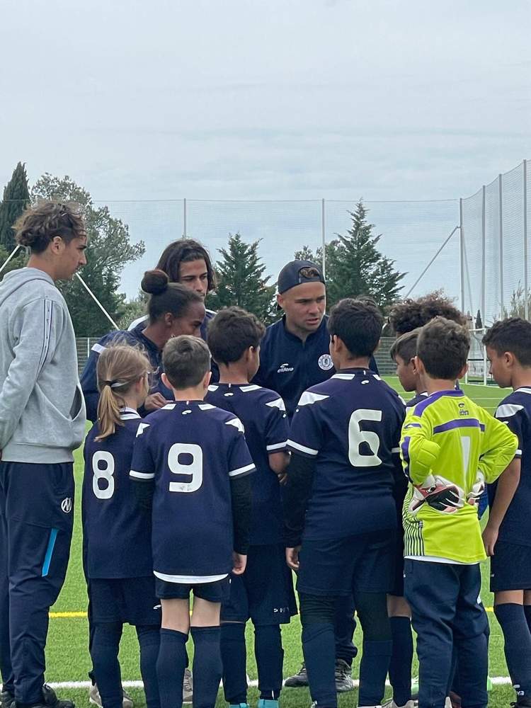 Des jeunes joueurs de football écoutent attentivement leur entraîneur sur le terrain.