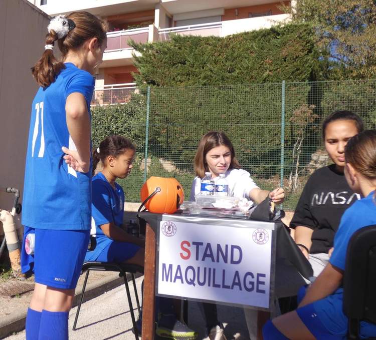 Des jeunes filles animent un stand de maquillage en extérieur.