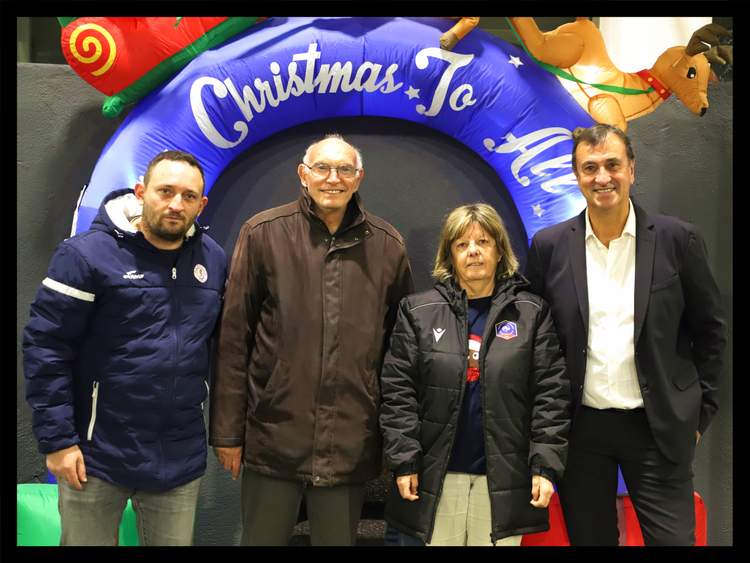 Quatre personnes posent devant une arche gonflable décorée pour Noël.