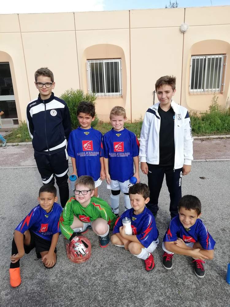 Un groupe de jeunes footballeurs pose pour une photo d'équipe devant un bâtiment.