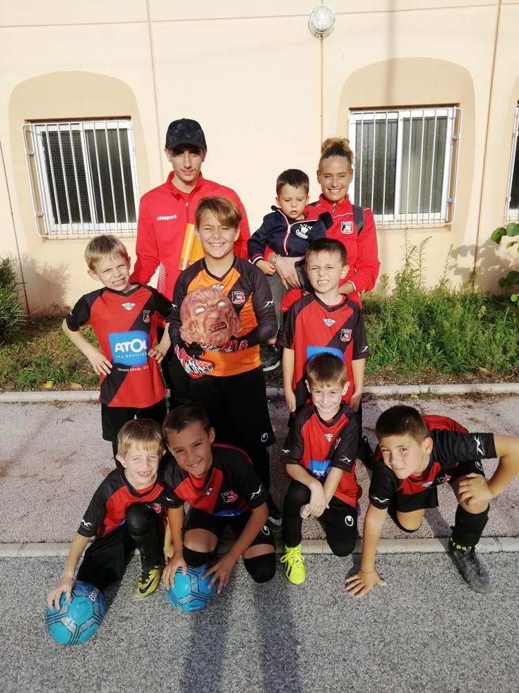 Une équipe de jeunes footballeurs pose avec leurs entraîneurs et un enfant en bas âge.